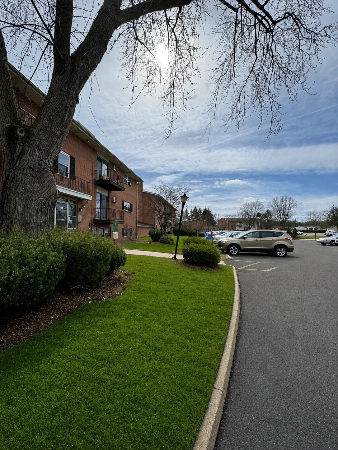Brick apartment building with private balconies and mature trees.